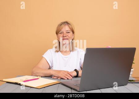 Portrait of beautiful happy smiling middle age designer woman sitting at home office desk and using computer Stock Photo