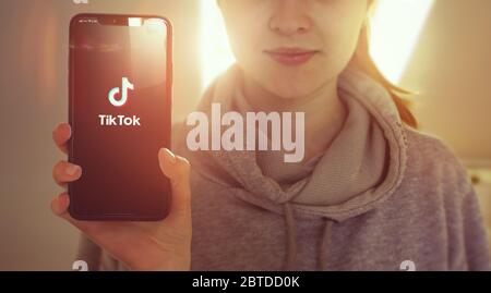 KYIV, UKRAINE-JANUARY, 2020: Tiktok on Smartphone Screen. Young Girl Showing Smartphone Screen with Tiktok on it while Looking at the Camera. Focus on Smartphone. Stock Photo
