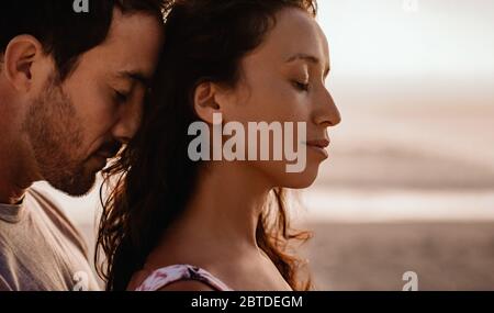 Loving couple standing close together on a beach at dusk Stock Photo