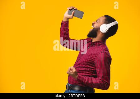 Afro man singing using smartphone as microphone Stock Photo