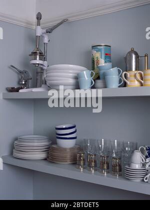 Juicer on shelving with white bowls and plates and blue cups Stock Photo