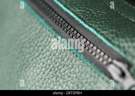 Zipper slider for a bag made of textured green leather. Handmade. Close up. Stock Photo