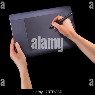 Hand holding digital graphic pen and drawing graphic tablet for illustrators, designers and photographers isolated on black background Stock Photo