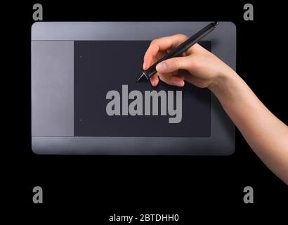 Hand holding digital graphic pen and drawing graphic tablet for illustrators, designers and photographers isolated on black background Stock Photo