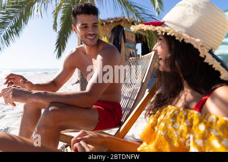 Caucasian couple  sitting on deck chairs at the beach Stock Photo
