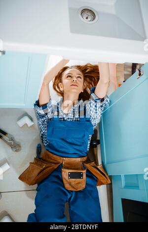 Female plumber lying on the floor, top view Stock Photo