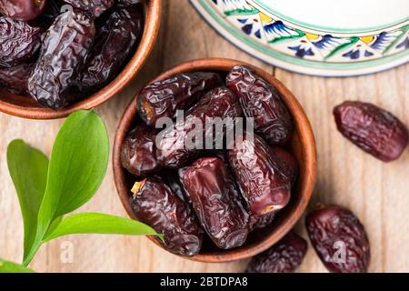 Dried dates in bowl on wooden table background, top view. Islamic Arabic food concept Stock Photo