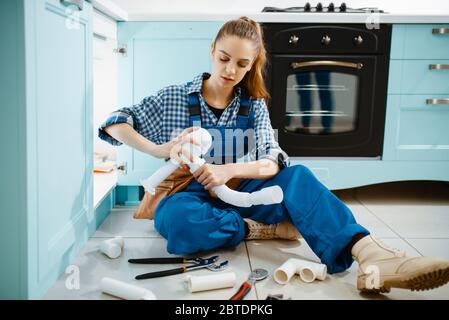 Female plumber fixing problem with drain pipe Stock Photo
