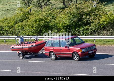 1998 90s red Land Rover Range rover 2.5 Diese; Auto Manchester Boat owners, towing leisure craft travelling on the M61 flock to the Lake District in spite of Cumbrian lockdown. Warnings have been issued that public toilets and cafes remain closed and that holidaymakers are unwelcome in Windermere. Stock Photo