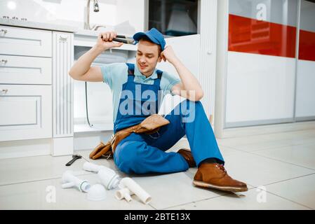 Smiling male plumber in uniform holds drain pipe Stock Photo