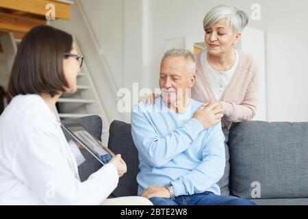 Portrait of modern senior couple listening to female doctor and looking at lung x-ray image during consultation in clinic Stock Photo