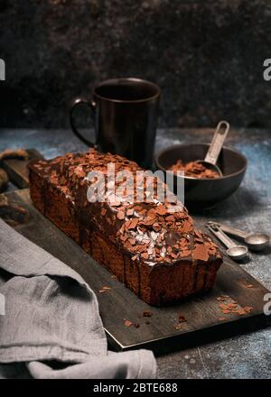 Freshly baked banana bread with chocolate chips and glaze. Homemade sweet concept. Dark food photography. Stock Photo