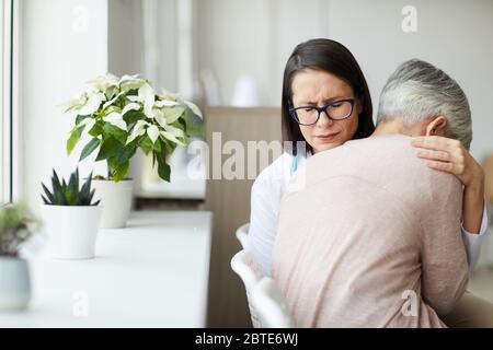 Portrait of crying female doctor hugging senior woman while trying to comfort her after bad news, copy space Stock Photo