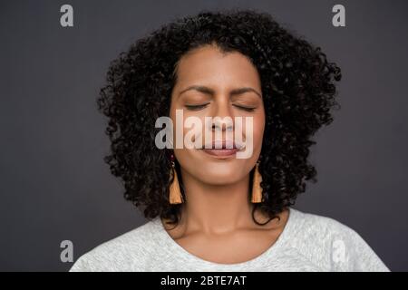 Content young woman standing with her eyes closed on gray Stock Photo