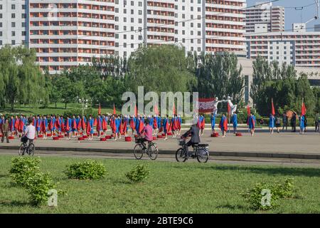 Women wave red flags to encourage people heading to work in Pyongyang, North Korea Stock Photo