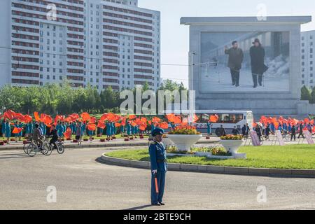 Women wave red flags to encourage people heading to work in Pyongyang, North Korea Stock Photo