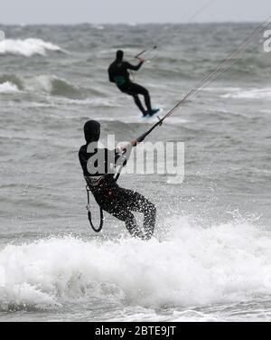 Mecklenburg, Germany. 25th May, 2020. 25 May 2020, Mecklenburg-Western Pomerania, Warnemünde: Wind and clouds make for grey dirty weather at the Baltic Sea, two kite surfers use the wind for their sport. Photo: Bernd Wüstneck/dpa-Zentralbild/dpa Credit: dpa picture alliance/Alamy Live News Stock Photo
