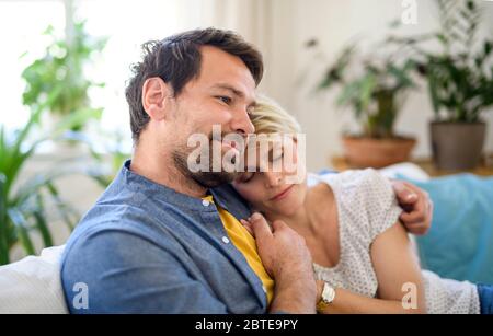 Happy couple in love sitting indoors at home, hugging. Stock Photo