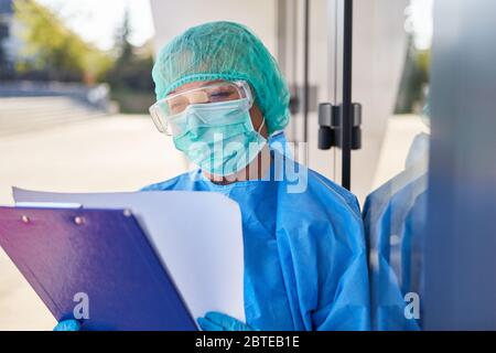 Employee as containment scout in front of clinic studies contact tracking list in coronavirus pandemic Stock Photo