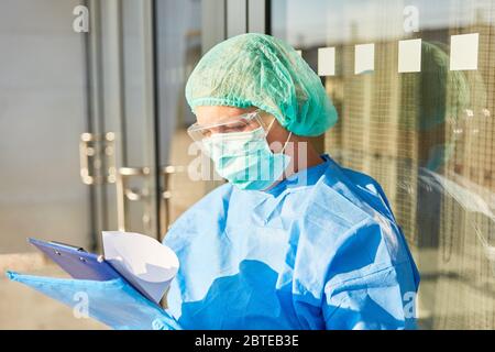 Containment scout in front of clinic or home entrance studies contact tracking list during Covid-19 pandemic Stock Photo