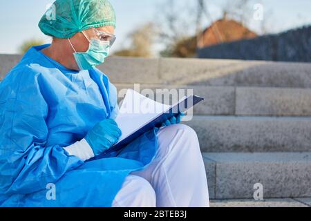 Containment Scout studies contact tracking list in front of clinic in case of coronavirus or Covid-19 pandemic Stock Photo