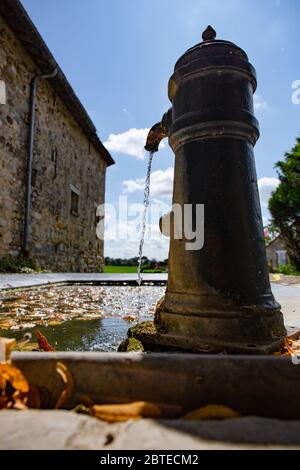 Old hand water pump and basin in a small village square Stock Photo