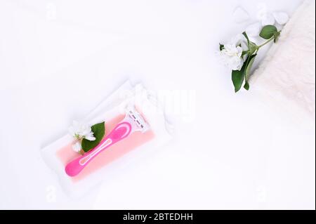 a set of different means for epilation on a colored background. Removal of unwanted hair. Body care products, towels, jasmine flowers, wax strips, razor. Minimalism, top view. flatlay. Stock Photo