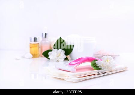 a set of different means for epilation on a colored background. Removal of unwanted hair. Body care products, creams, emulsion,towel, jasmine flowers, wax strips, razor. Minimalism, top view. flatlay. Stock Photo