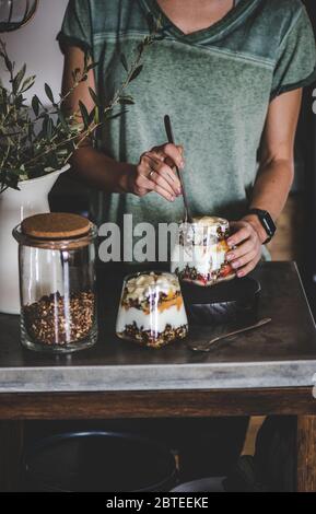 Woman having healthy breakfast with yogurt, granola and fruit Stock Photo