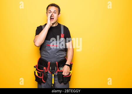 Portrait of repairman screaming while holding wires against yellow background Stock Photo
