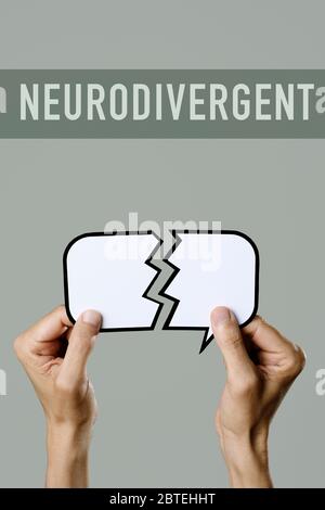 closeup of a young caucasian man holding a broken speech balloon in his hands and the text neurodivergent on a gray background Stock Photo