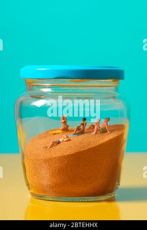 some miniature people wearing swimsuit relaxing on the sand in a glass jar, symbolizing different ideas, such as the greenhouse effect or the protecti Stock Photo
