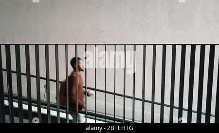 a silhouette of a black man descending the stairs down behind the metal railing Stock Photo