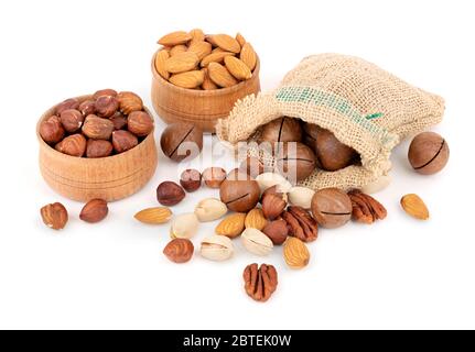 Variety of nuts in sack and wooden bowls on white background. Vegan healthy food concept Stock Photo