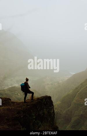 A girl standing on a cliff at Cape of Good Hope with the Atlantic ocean ...