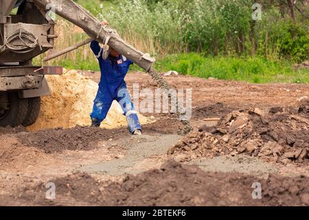 Construction worker laying cement or concrete into the foundation formwork. Building house foundation Stock Photo