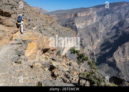 Female hiker at edge of Balcony Walk above Wadi Nakhar, Jebel Shams in Oman Stock Photo