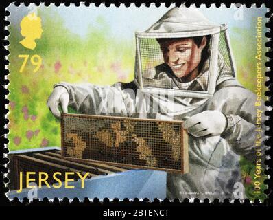Beekeeper holding a brood frame on postage stamp Stock Photo