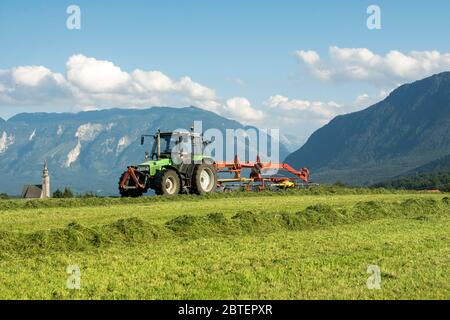 der Landwirt bei der Arbeit zum Einbringen von Heu oder Siilage mit Anger und dem Untersberg im Hintergrund Stock Photo