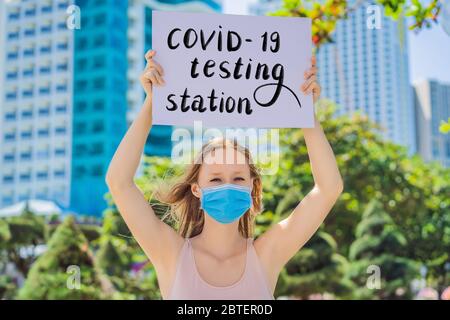woman in medical mask prevents coronavirus disease holds a poster coronavirus testing sign Hand written text - lettering isolated on white Stock Photo