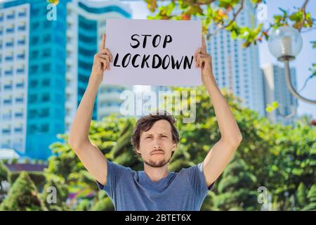 man holds a poster Stop lockdown. Hand written text - lettering isolated on white. Coronovirus COVID 19 concept Stock Photo