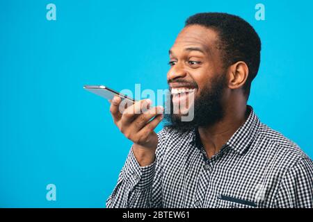 Happy afro man using voice assistant on smartphone Stock Photo