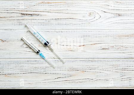 Top view of syringes of different sizes on wooden background. Medical equipment for injection concept with copy space. Stock Photo