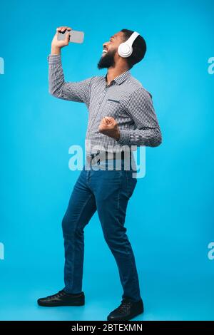 Afro man singing using smartphone as microphone Stock Photo