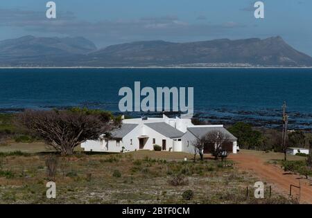 Kleinmond, Western Cape, South Africa. 2019.  A large house standing alone on the shoreline close to Kleinmond with a view across Walker Bay, Western Stock Photo