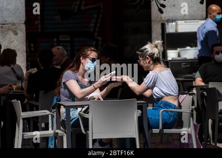 Madrid, Spain. 25th May, 2020. A customer wearing protective face mask in an outdoor terrace table of a cafe in Plaza Mayor using hand sanitizer. Madrid has entered the so-called Phase One transition of the coronavirus lockdown, allowing many shops to reopen as well as restaurants to serve customers outdoors. Credit: Marcos del Mazo/Alamy Live News Stock Photo