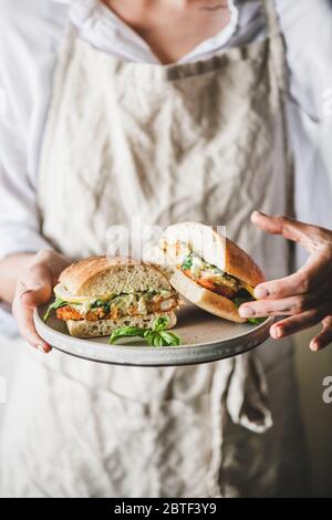 Woman holding plate with fresh fried fish sandwich in halves Stock Photo