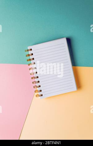 Open notebook with blank sheet and golden spiral on a colorful pastel background. The concept of education, writing down ideas, plans. Place for text. Stock Photo