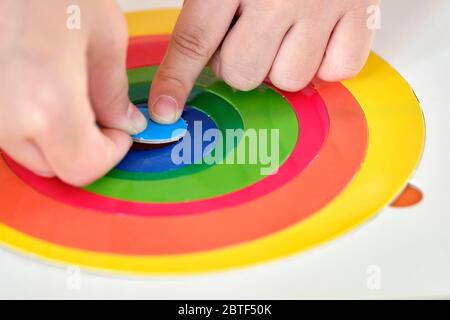 Close up. Child’s hand, kid’s hand is putting last piece jigsaw of color puzzle on the target. Target achievement. Stock Photo
