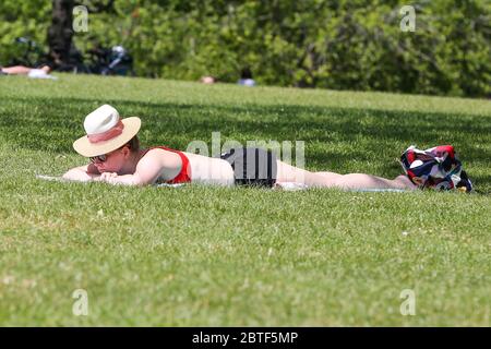 A woman reads a book while sunbathing during summer in Montevideo ...